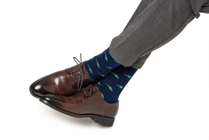 A person stepping forward wearing a brown leather shoe and Stegosaurus socks with whimsical green accents.