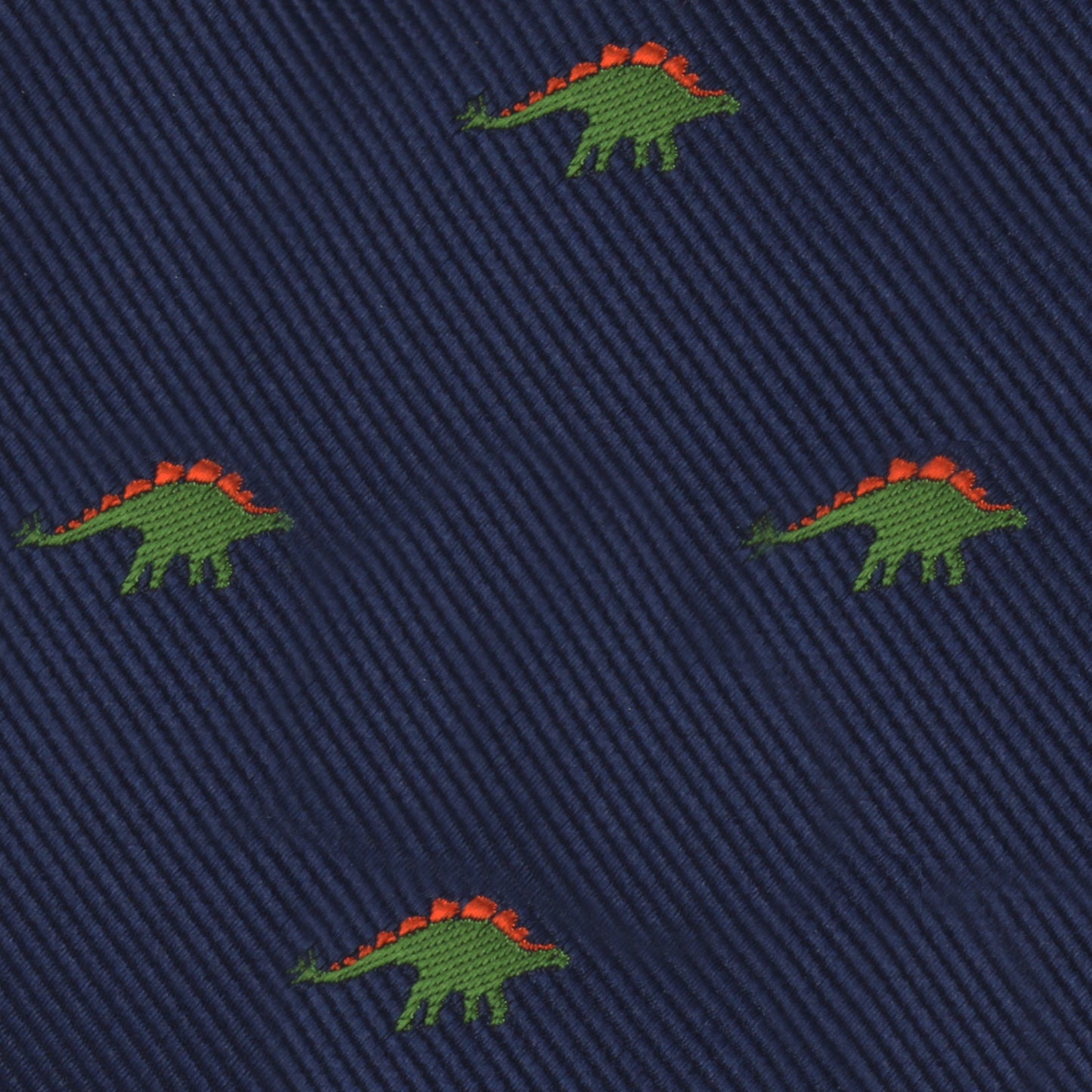 The Stegosaurus Bow Tie features a navy blue fabric adorned with small embroidered green dinosaurs, each sporting orange spines, adding a touch of prehistoric panache.