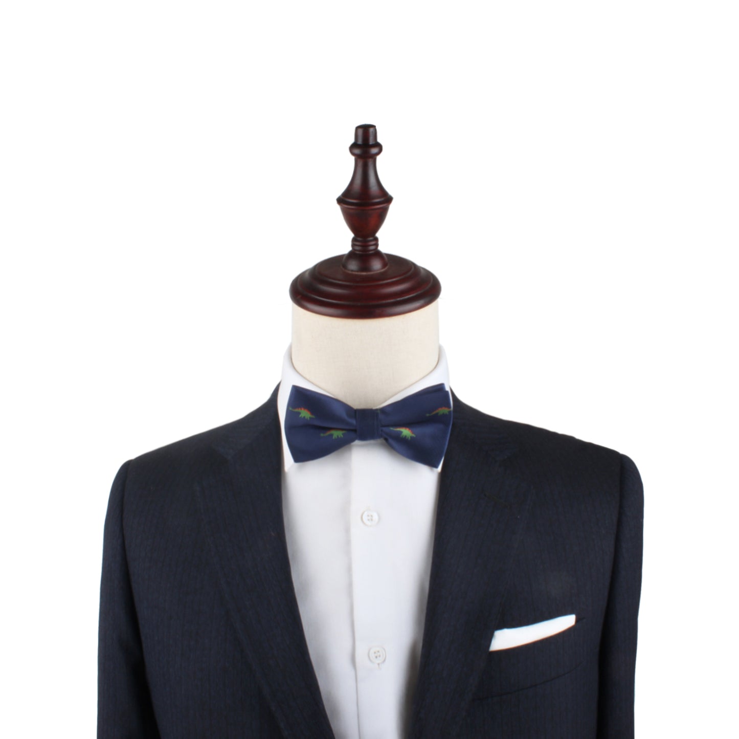 A suit jacket, white dress shirt, and a Stegosaurus Bow Tie featuring green accents are displayed on a mannequin with a wooden top, showcasing timeless panache.