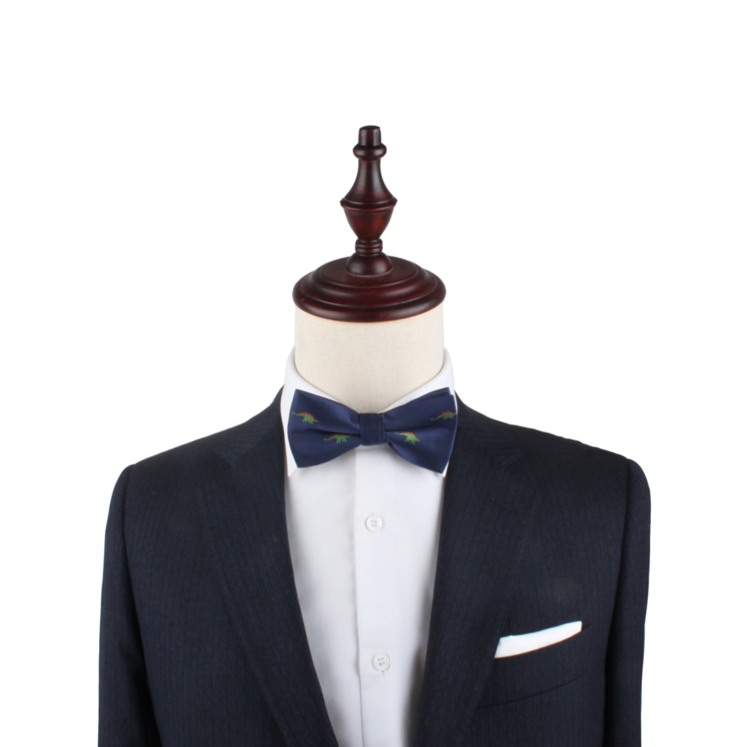 A suit jacket, white dress shirt, and a Stegosaurus Bow Tie featuring green accents are displayed on a mannequin with a wooden top, showcasing timeless panache.