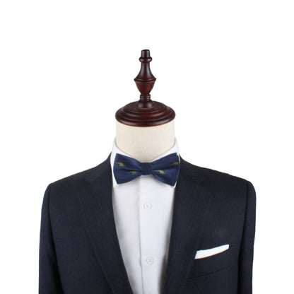 A suit jacket, white dress shirt, and a Stegosaurus Bow Tie featuring green accents are displayed on a mannequin with a wooden top, showcasing timeless panache.