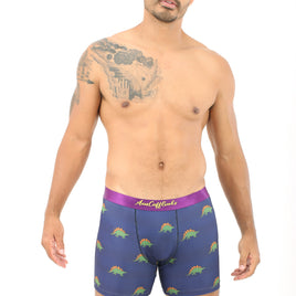 A tattooed man models Stegosaurus Boxer, featuring blue dinosaur patterns and a purple waistband for dino-sized snugness.