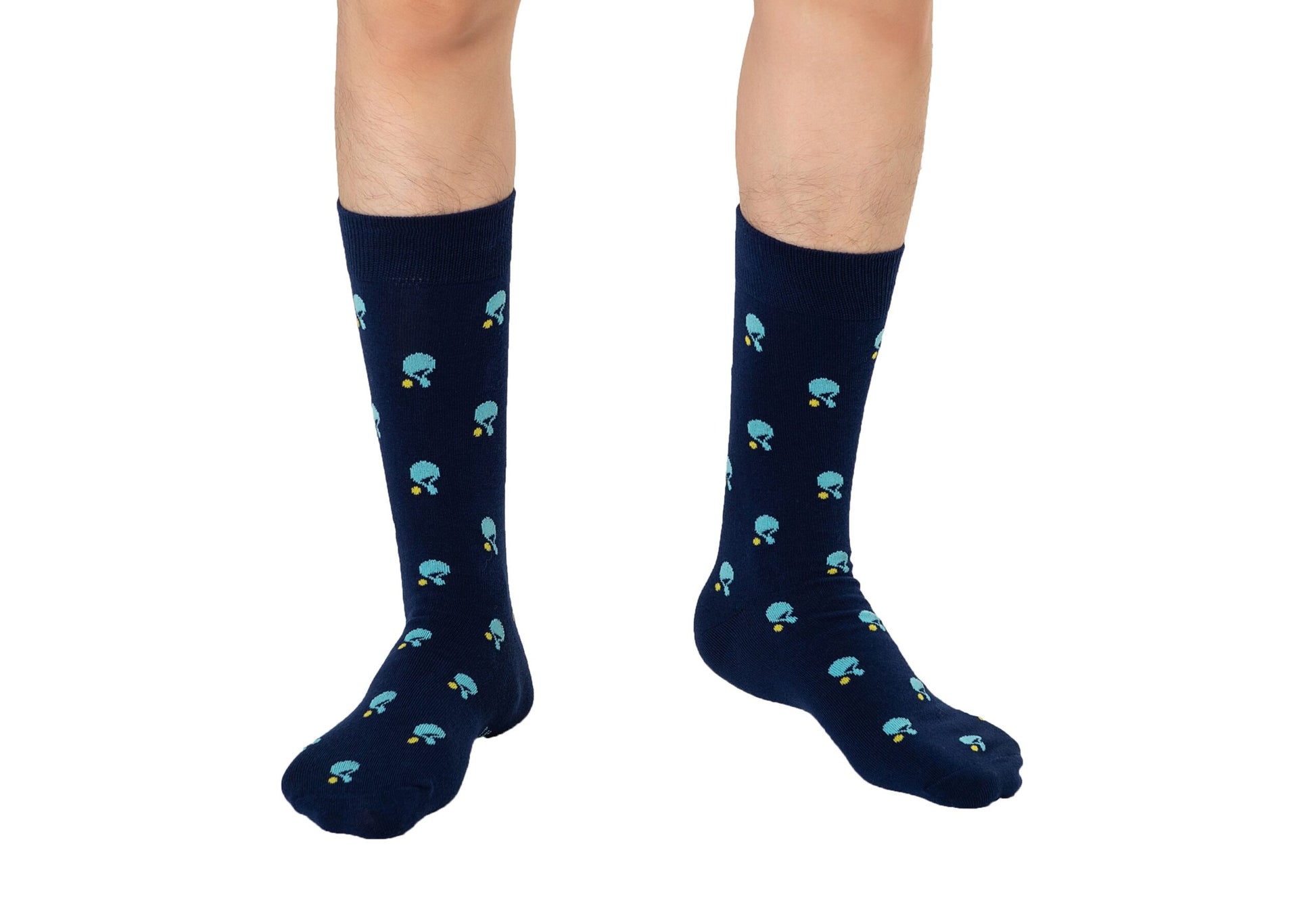 A person stands on a white background wearing navy blue Table Tennis Socks, featuring a pattern of small blue mushrooms and crafted from breathable fabric.