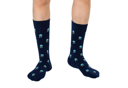 A person stands on a white background wearing navy blue Table Tennis Socks, featuring a pattern of small blue mushrooms and crafted from breathable fabric.