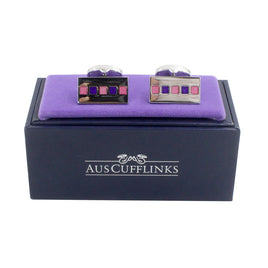 The Tiled Pink Purple Cufflinks boast a striking square design, presented on a purple cushion inside a sleek black box labeled "AUS Cufflinks," making them the ideal formal accessory.