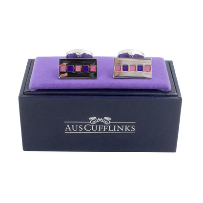 The Tiled Pink Purple Cufflinks boast a striking square design, presented on a purple cushion inside a sleek black box labeled "AUS Cufflinks," making them the ideal formal accessory.