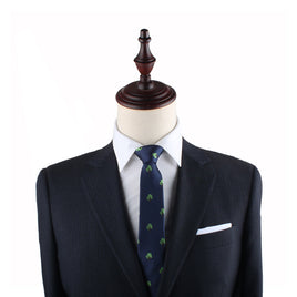 A mannequin is dressed in a dark business suit with a white dress shirt and the Tree Thin Tie, featuring a small green pattern that blends nature's allure into sophisticated fashion.