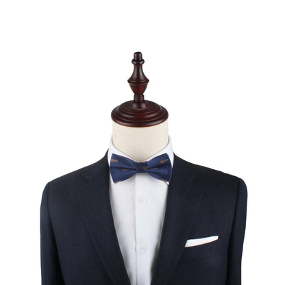 A mannequin sports a tailored dark suit and white shirt, accented by a chic Triceratops Bow Tie, set against a plain white background.