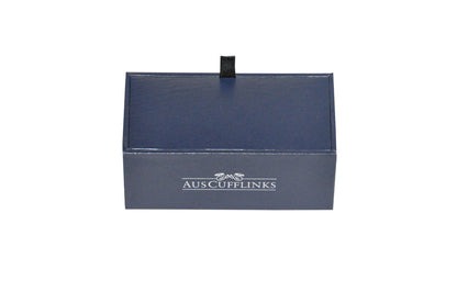 A navy-blue Aus Cufflinks box with a black pull tab on top, adorned with the brand logo in white. Inside, find the Turquoise Square Cufflinks offering timeless elegance to enhance any outfit.