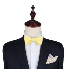 Mannequin displays the modern gentleman's style with a premium black cotton suit, enhanced by a Yellow Self Tie Bow Tie and a floral pocket square, set against a plain white backdrop.