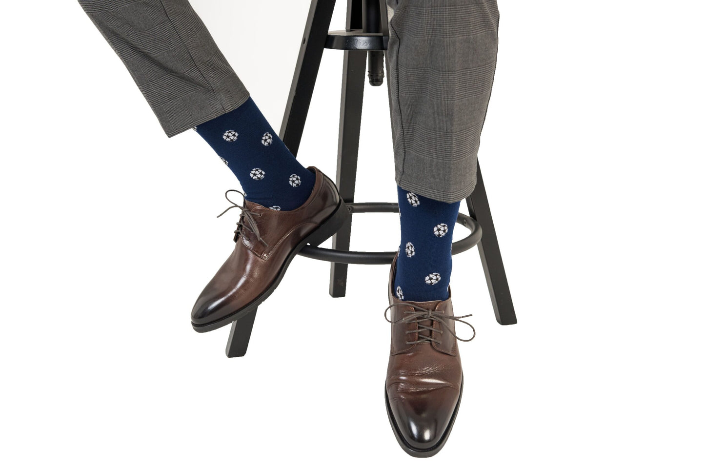 A seated person wearing gray pants, Soccer Socks, and brown leather dress shoes exudes goal-worthy comfort with every step.