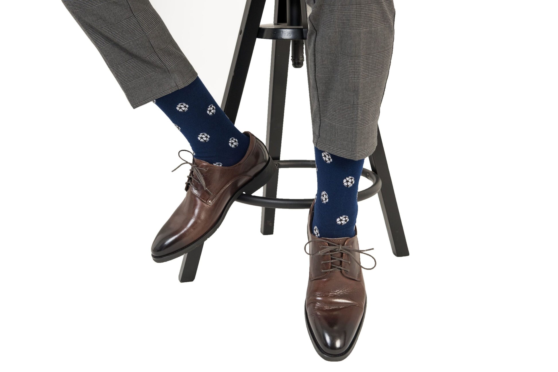 A seated person wearing gray pants, Soccer Socks, and brown leather dress shoes exudes goal-worthy comfort with every step.